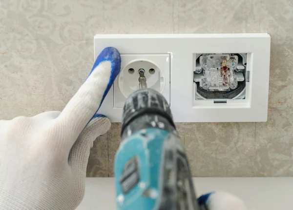 Electrician installs electrical outlet.
