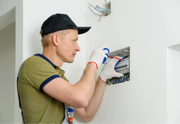 Electrician installing an electrical fuse box .