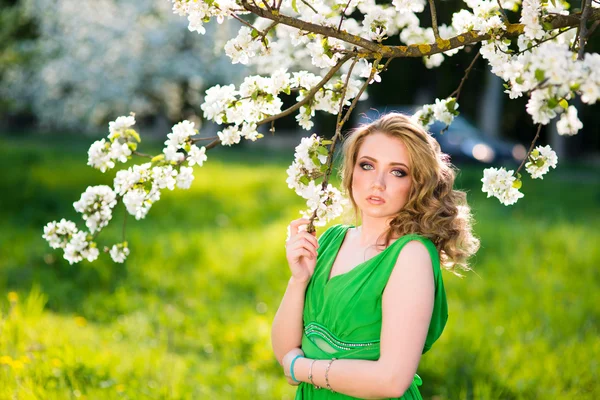 Fashion beautiful blonde woman in blossoming garden of Apple trees