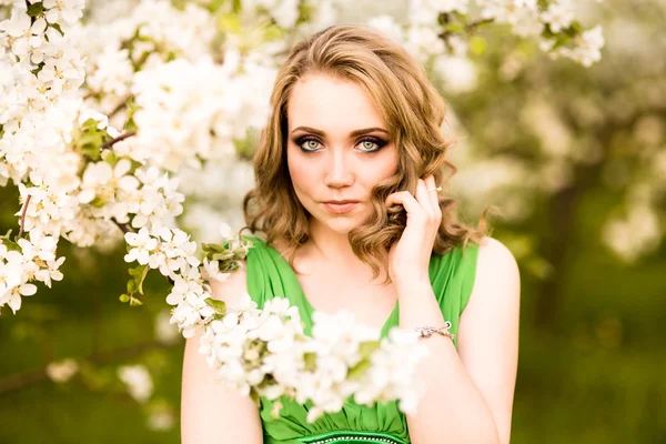 Fashion beautiful blonde woman in blossoming garden of Apple trees