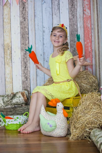 Beautiful girl in the yellow dress, playing with carrot