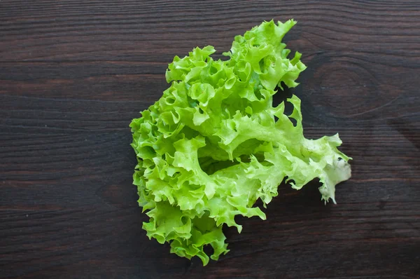 Fresh green salad leaves (lettuce) on black wooden table