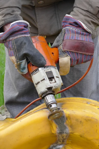 Worker brushing metal with power tool