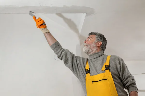 Worker repairing plaster at ceiling