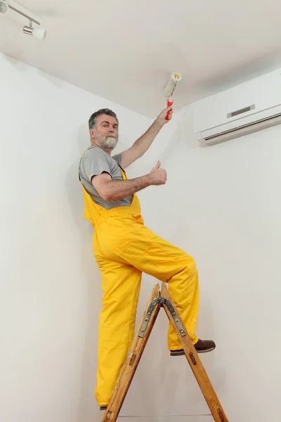 Worker painting ceiling in room