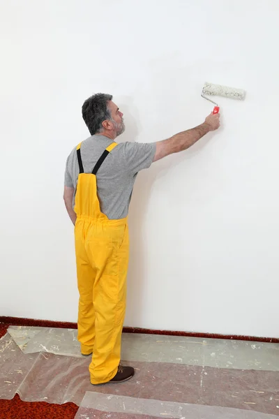 Worker painting wall in room