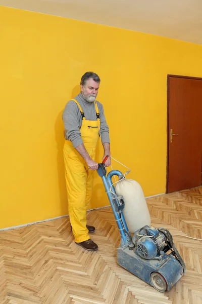 Home renovation, worker sanding parquet