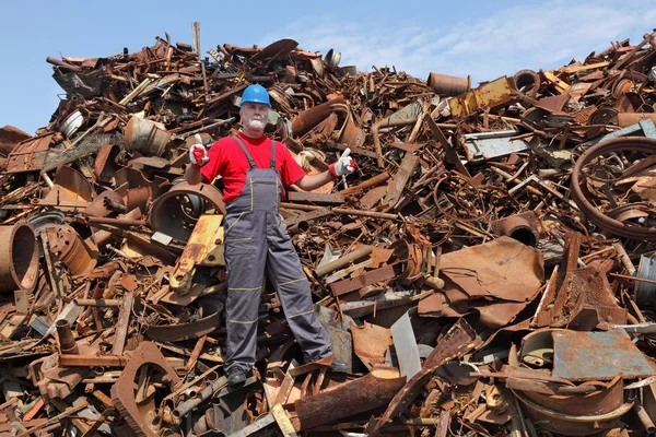 Recycling industry, worker gesture at heap of old scrap metal