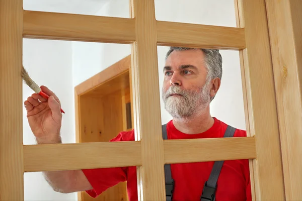 Home renovation, worker painting wooden door, varnishing