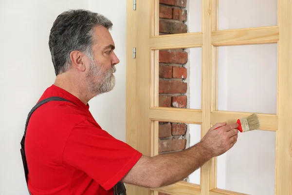 Home renovation, worker painting wooden door, varnishing