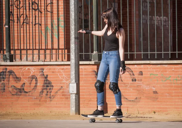 Beautiful young woman practicing with the skateboard on the stre