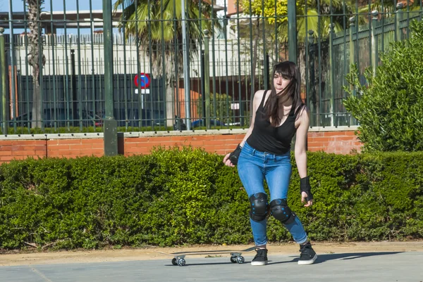 Beautiful young woman practicing with the skateboard on the street