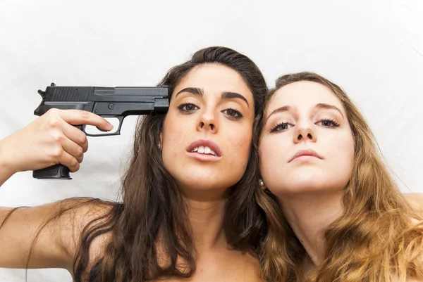 Portrait of two beautiful women in which one points a gun to the