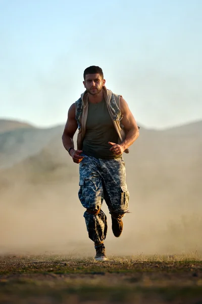 Athletic young man exercising outdoor on dusty field