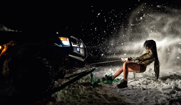 Young athletic woman pulling car in winter