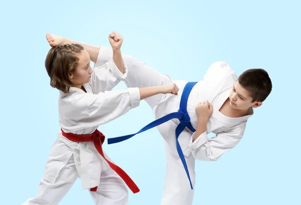 On a light background athletes train blocks and kicks of karate