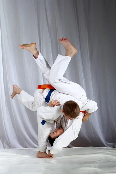 Sportsmen with a blue and orange belt are doing judo throws