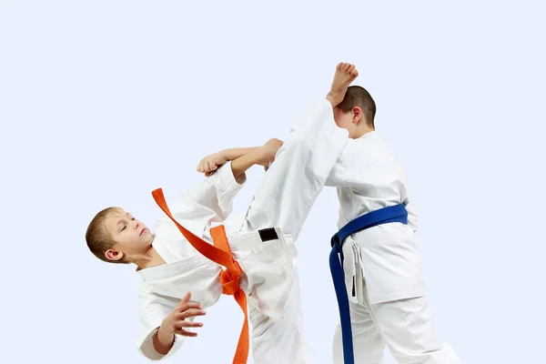 The athlete with the orange belt beats athlete with a blue belt blow leg on the head