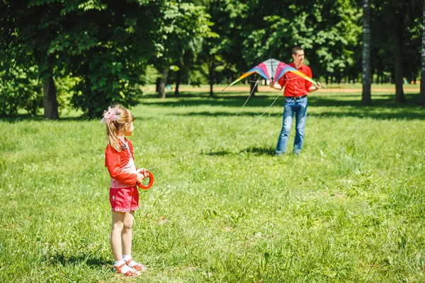 The girl and her father play with a kite.