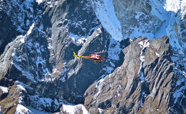 Helicopter is flying between snow mountains peak in high Himalayan mountains , Nepal