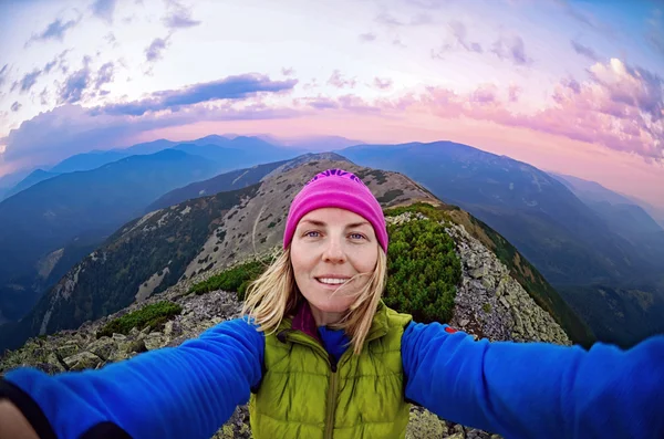 Smiling young woman takes a selfie  on  the  top of   mount Great Sivulja
