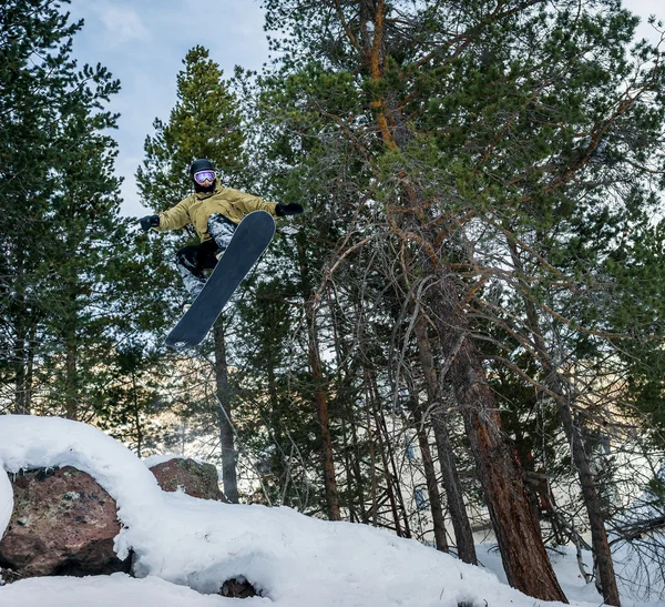 Snowboarder jumping in the forest