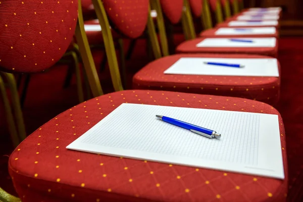 Chairs with notepads and pens in empty conference room