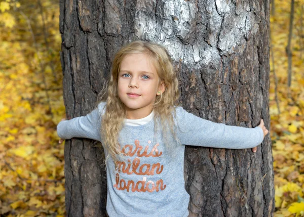 Beautiful young girl hugging tree