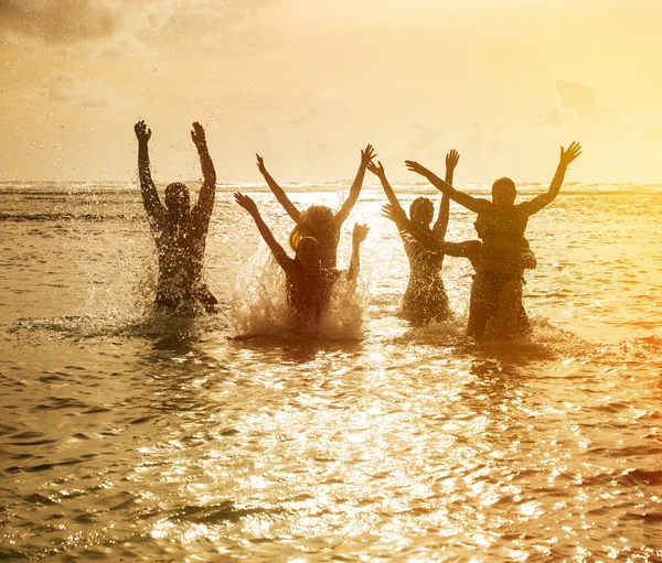 Silhouettes of people jumping in ocean