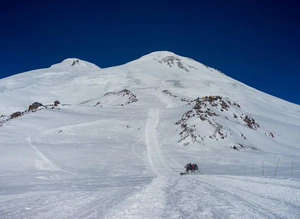 Snowcat with people rises up the hill