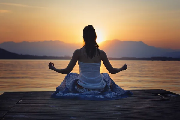 Woman meditation in front of golden sunset