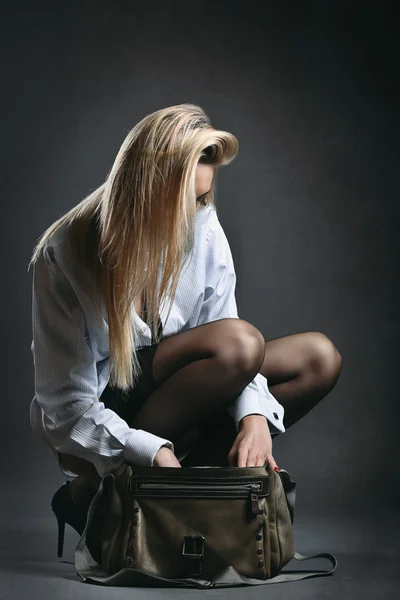 Blond hair model in stocking looks inside her bag