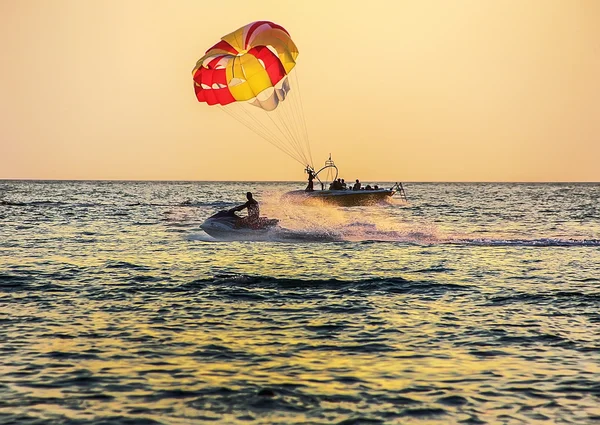 Boat with parachute and water bike at sea
