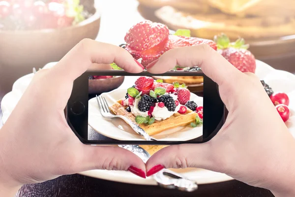 Female photographing waffles with ice cream