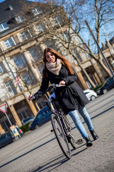 Pretty young woman holding her bicycle