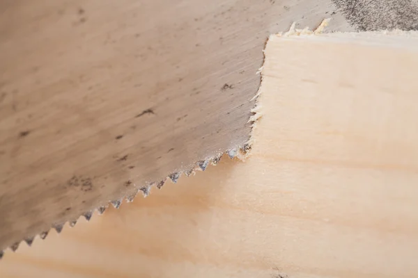 Hand saw cutting through a beam of wood