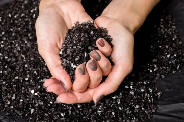 Female hands holding black decorative crystals