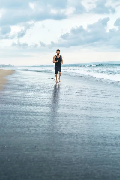 Fitness Man Running On Beach. Runner Jogging During Outdoor Workout