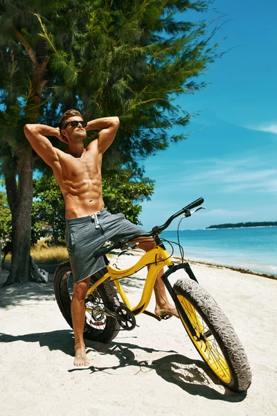 Handsome Man With Bike Sun Tanning On Beach. Summer Vacation.