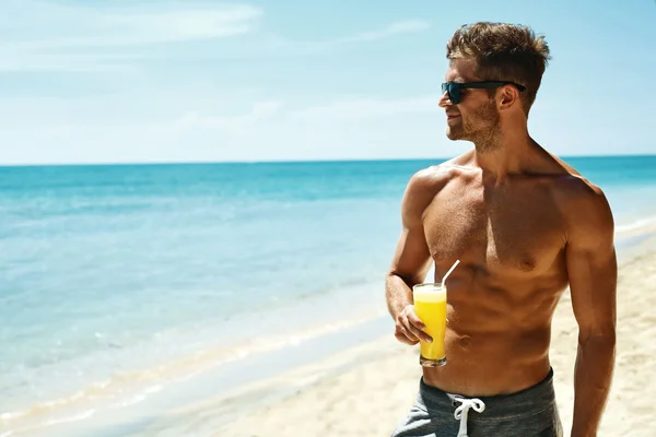 Summer. Athletic Muscular Man Drinking Juice Cocktail On Beach