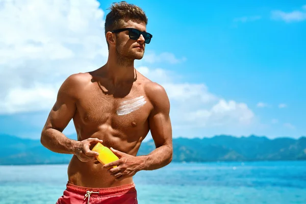 Man Tanning Using Sun Block Body Cream On Summer Beach