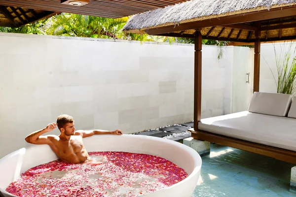 Man Relaxing In Spa Bath With Flowers Outdoors In Day