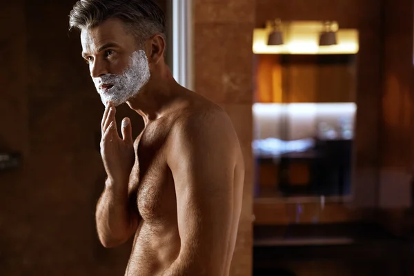 Man Using Shaving Cream On Face In Bathroom. Men Skin Care