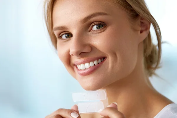 Teeth Whitening. Beautiful Smiling Woman Holding Whitening Strip