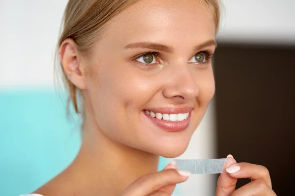 Woman Using Teeth Whitening Strip For Beautiful White Smile