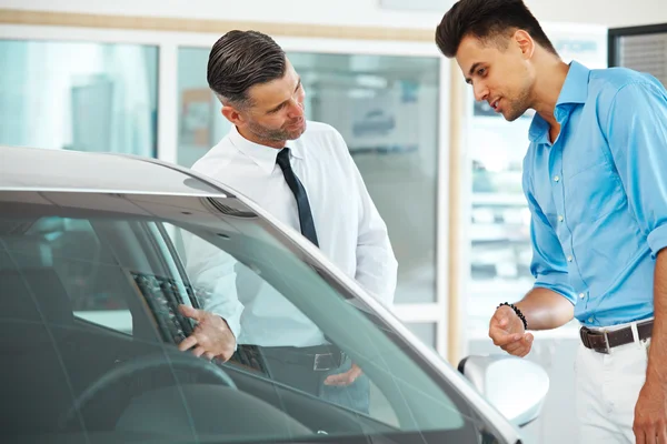 Car Sales Consultant Showing a New Car to a Potential Buyer