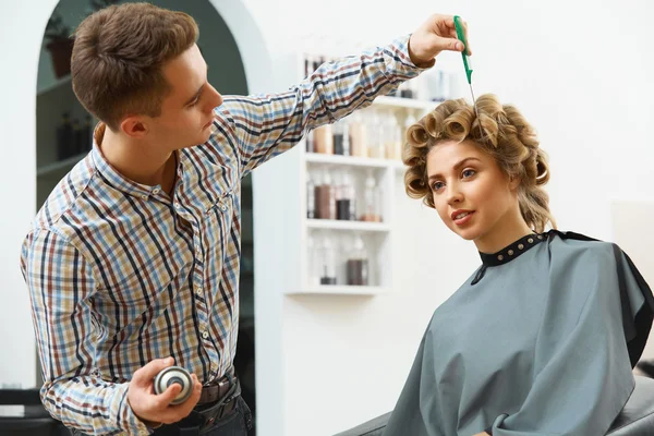 Hairdresser doing hairstyle for  woman