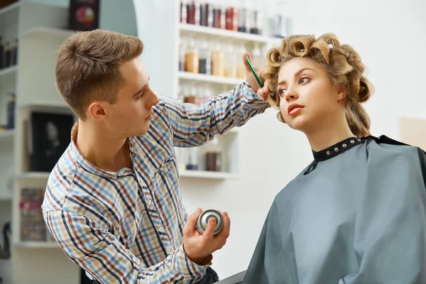 Hairdresser doing hairstyle for  woman
