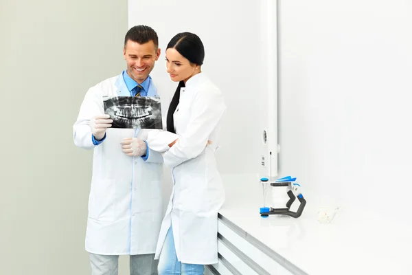 Dentist and female assistant are discussing dental X Ray image