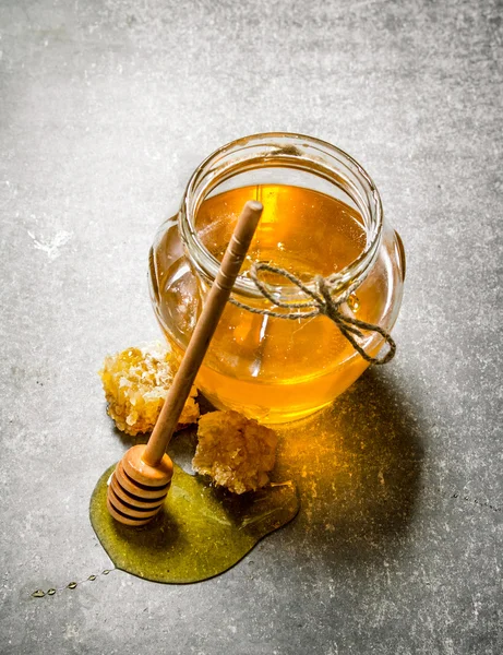 Glass jar with honey . On stone table.